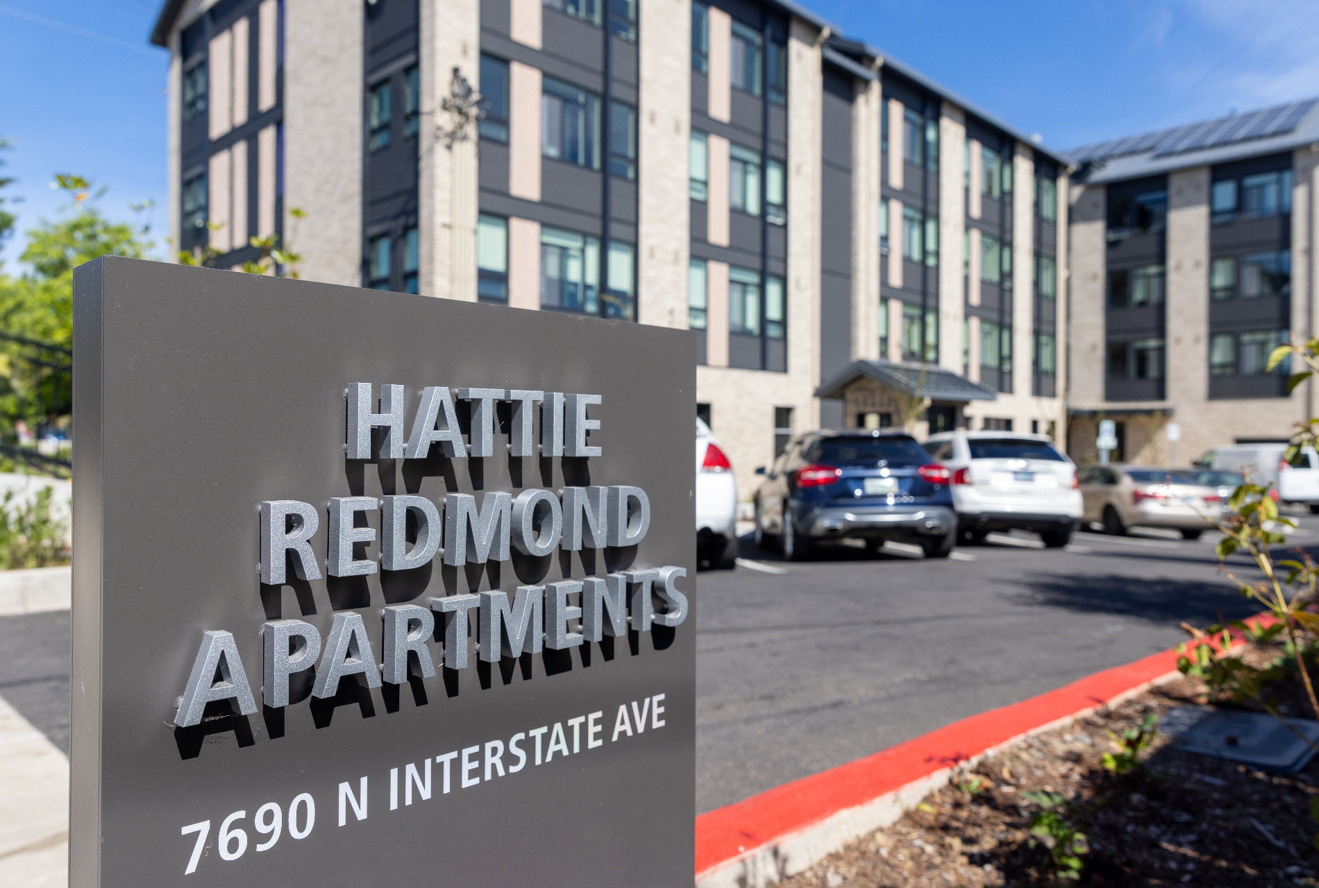 Photo of a sign saying Hattie Redmond apartments in front of building.