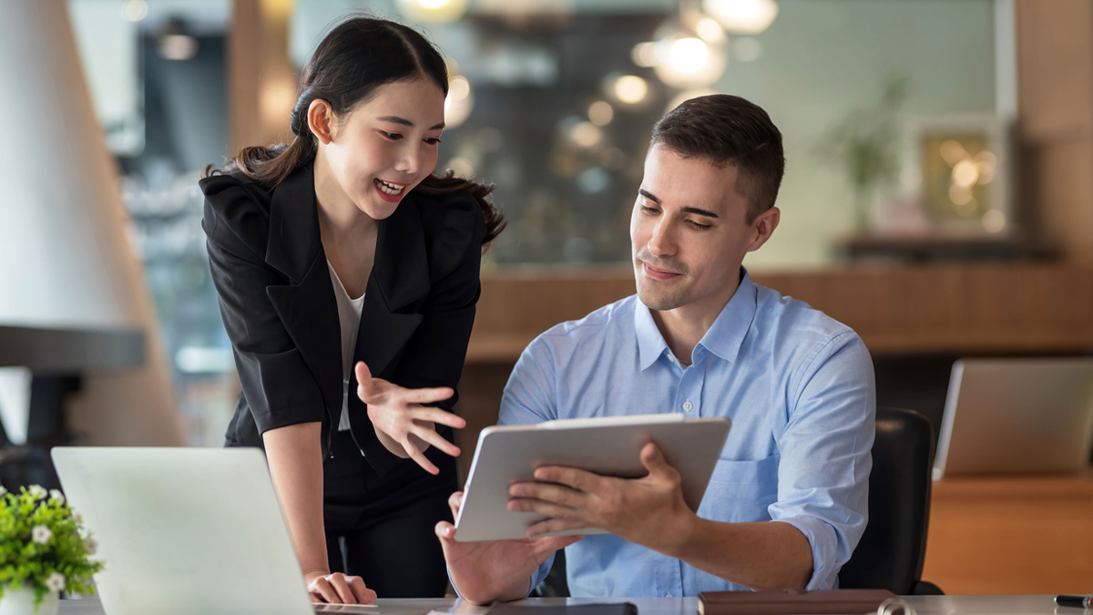 Business professional woman and man looking at a tablet in a business setting.