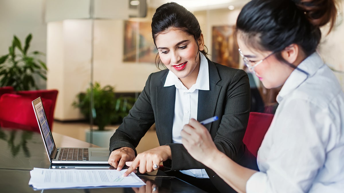 Two women signing account paperwork