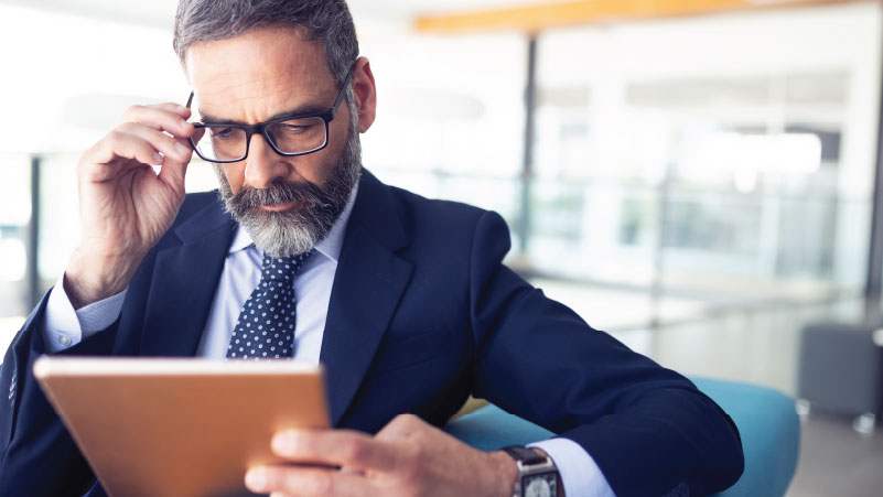 Man looking at notebook and adjusting his glasses.