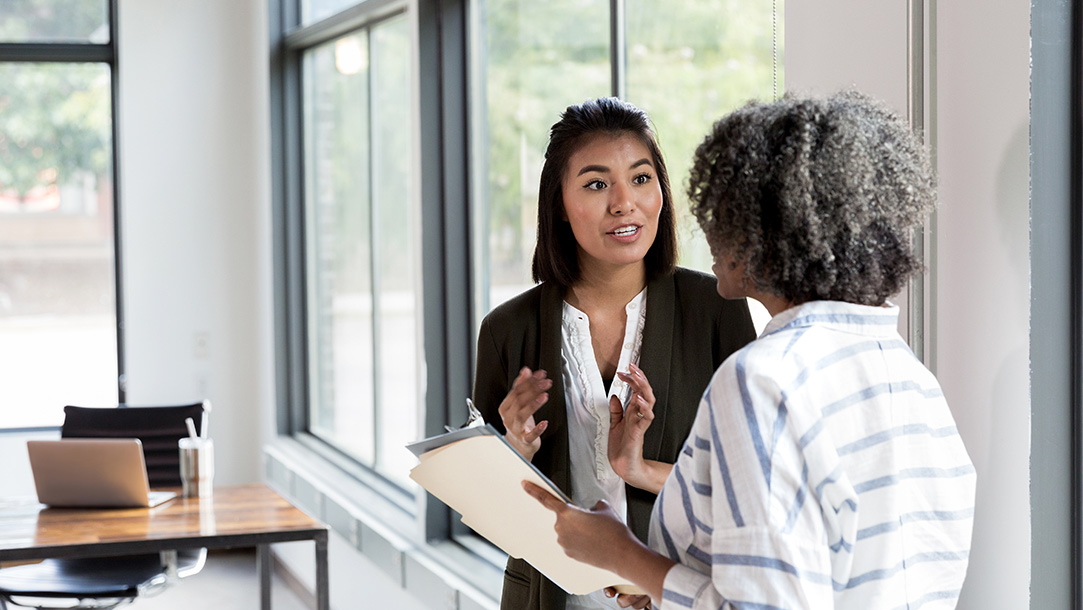 Two people talking in front of an office window