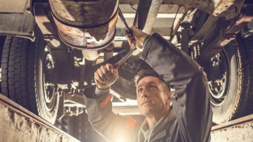 Mechanic working underneath lifted vehicle