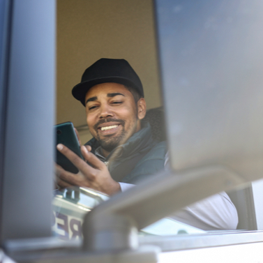 Fleet driver sitting in cab looking at mobile phone