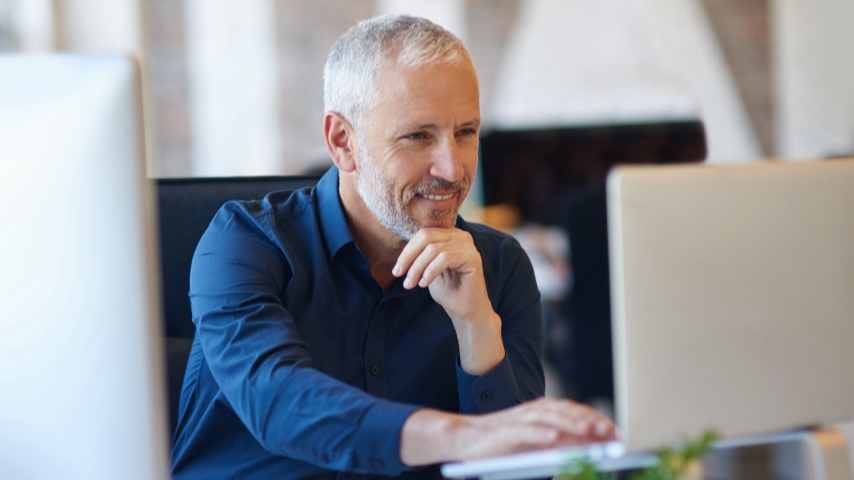 A person sitting while using a laptop at a desk.