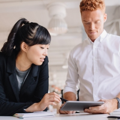 A man and woman working on a tablet in an office