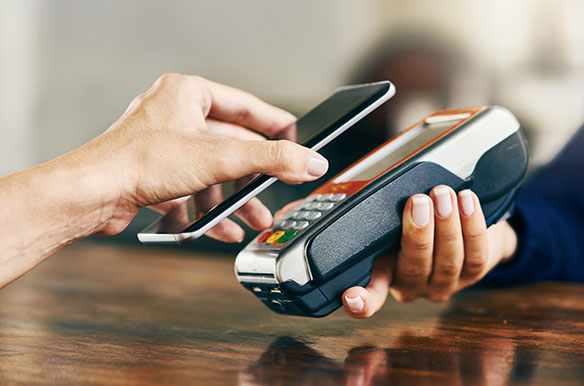 Person using her phone to scan and pay a bill on a card machine