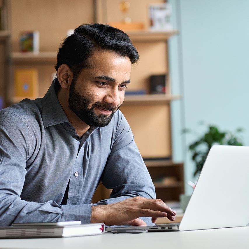 Man at a desk browsing the internet on a laptop