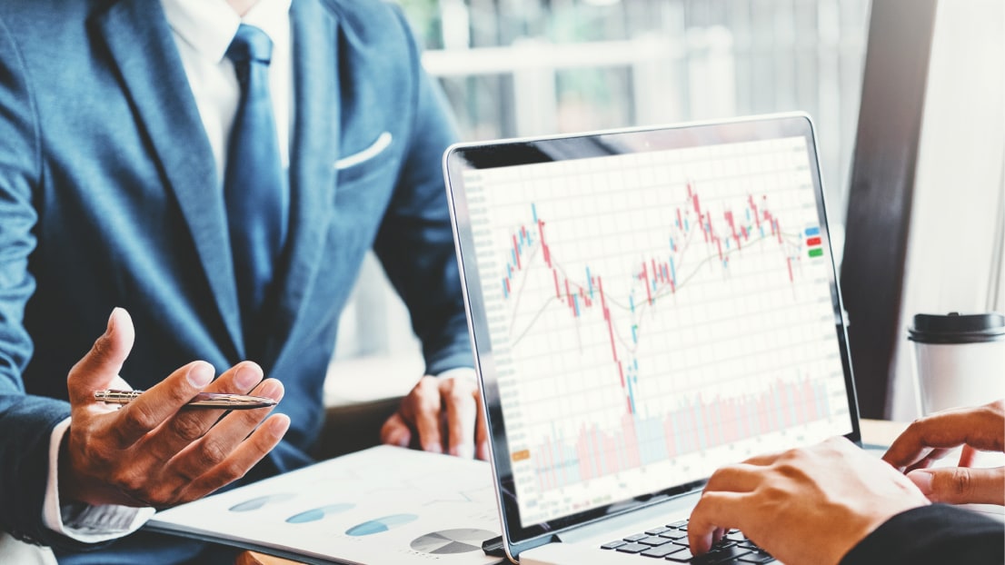 Person looking at a laptop screen showing stock charts.