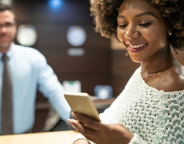 Woman using phone at hotel front desk.