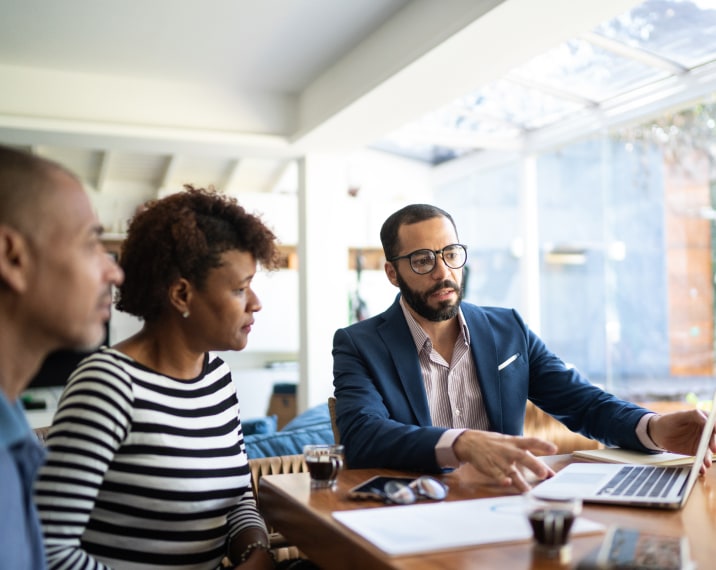 Three people around a table looking at a computer and paperwork.